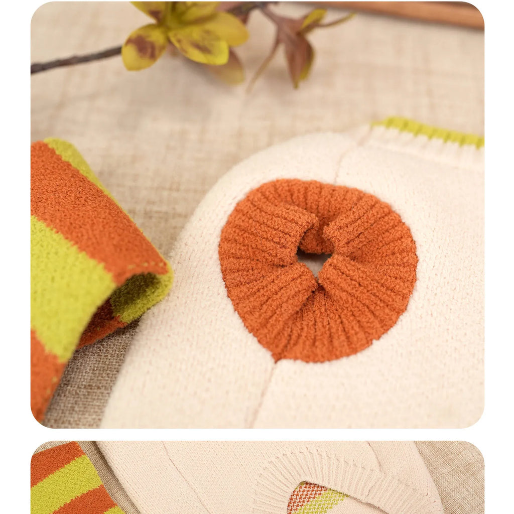 Close-up of the cream sweater ribbed orange arm opening and striped scarf